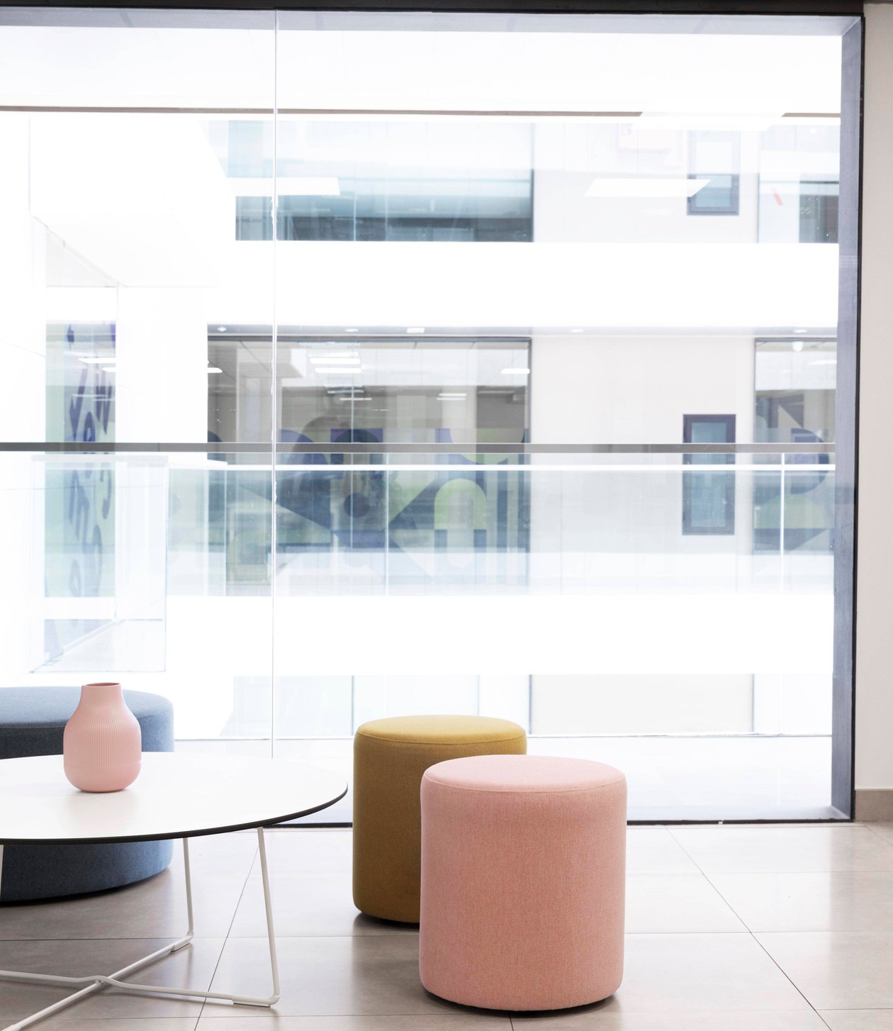 Bright commercial office breakout area with glazed partitions and soft seating.