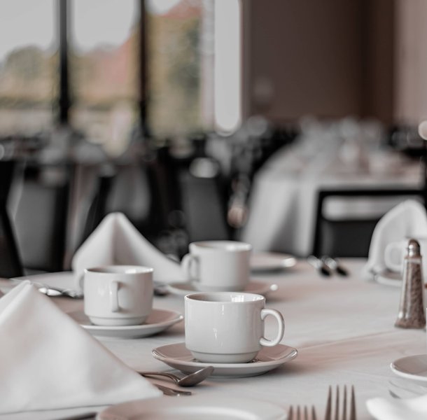 Restaurant dining room set with white linen and crockery.